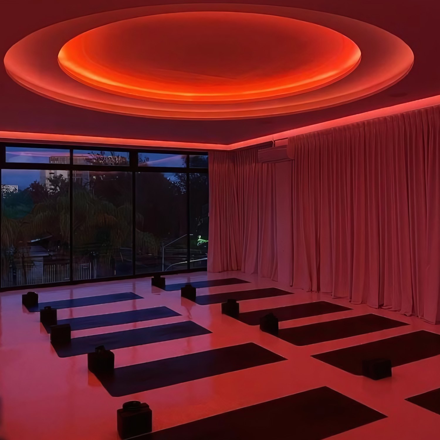 Referencia: óvalo de luz roja en el techo de una sala con cortinas rojas y colchonetas