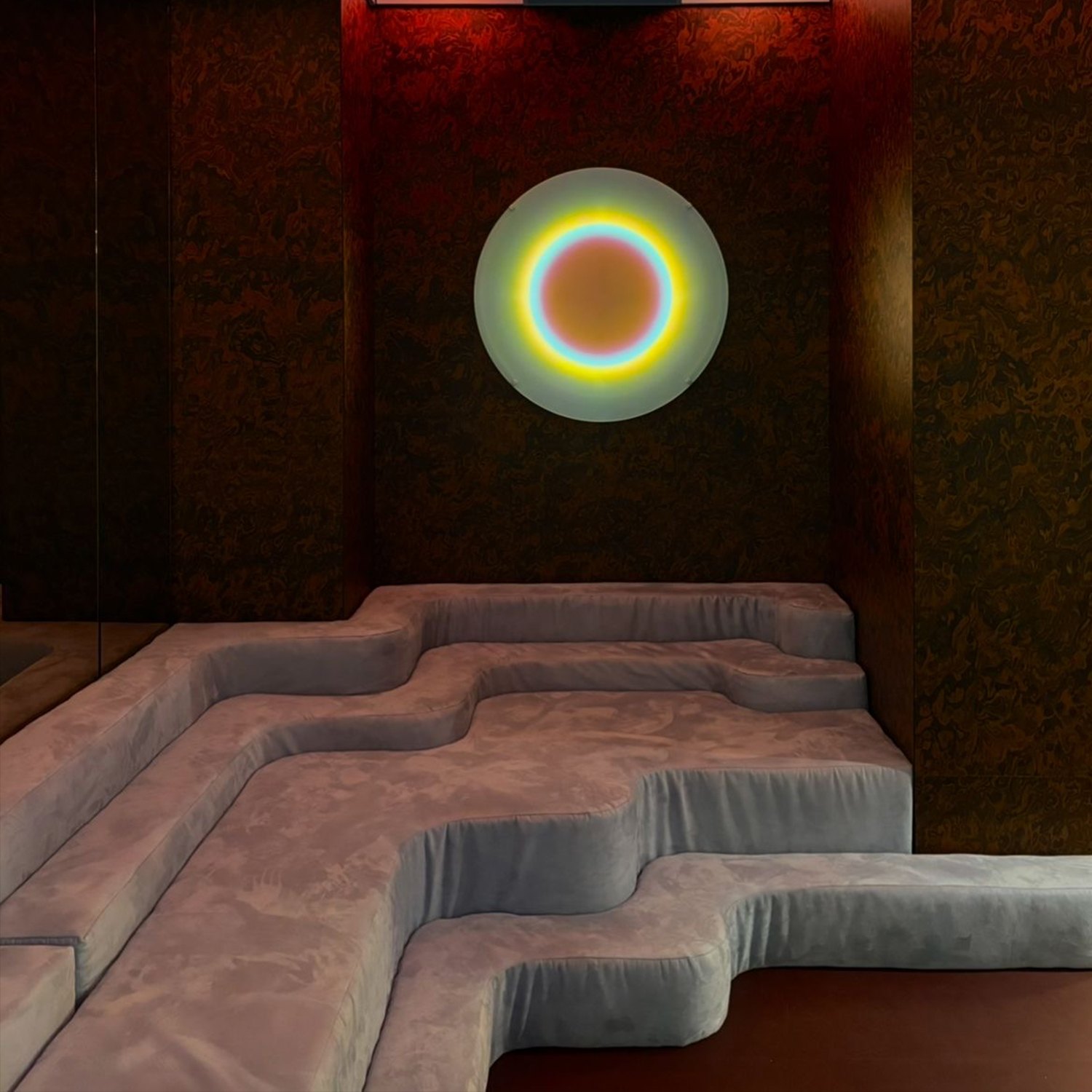 Referencia: círculo de luz con aro de colores sobre un sillón escalonado