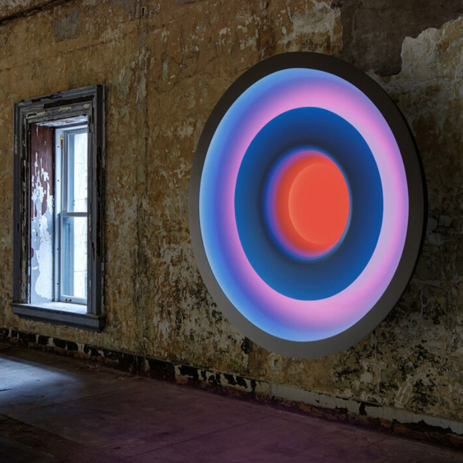 Referencia: disco de luz con círculos concéntricos azules y rosados sobre una pared antigua